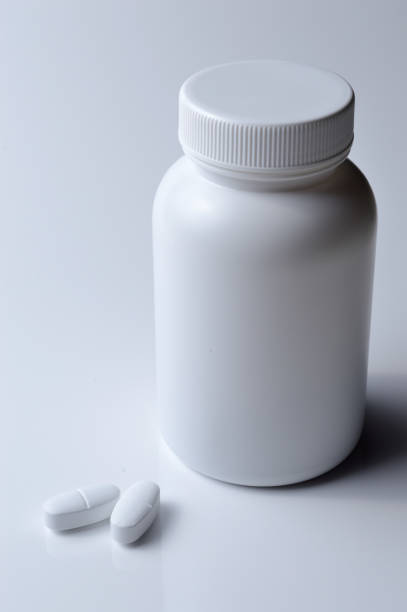 istock white plastic medicine jar and two white pills. light background. 1392592240
