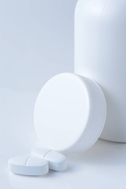 istock white plastic medicine jar and two white pills. light background. 1392592302
