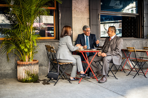 Three business people sitting at cafe and talking