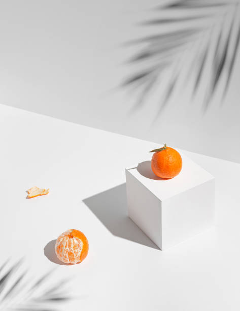 istock Creative composition made of fresh mandarin fruits on white sunlit background with shadows and geometric cube. Healthy food and summer refreshment concept. Minimal style. 1392593645