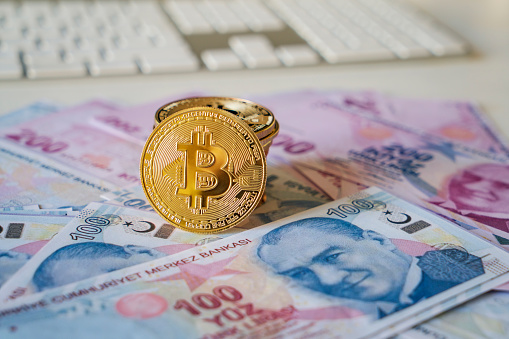 Istanbul, Turkey, January 5, 2022: Close up bitcoin coin with Turkish lira banknotes on background