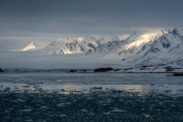 istock Snowy mountains with peaks in the clouds. In Svalbard, Norway. Global Warming. 1392594429