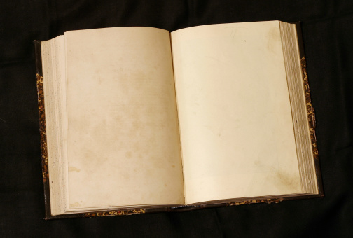 Old 19th century book open on both blank pages with stains and scratches.