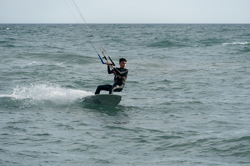 Barcelona, Spain - April 8 , 2022: Teenager surfing with a serious attitude on his surfboard at sunset