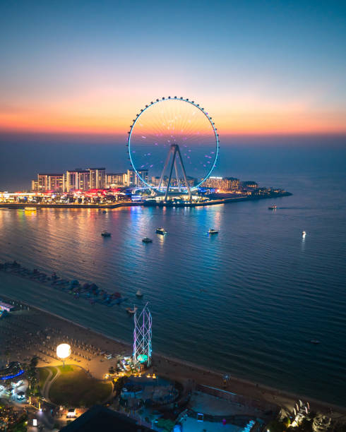 Bluewaters island leisure spot in Dubai with large Ferris wheel seen from JBR beach in Dubai Marina area Bluewaters island leisure spot in Dubai with large Ferris wheel seen from JBR beach in Dubai Marina area at blue hour. United Arab Emirates travel destination dubai island stock pictures, royalty-free photos & images