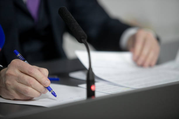 istock Politician with clasped hands sitting behind desk. 1392603956