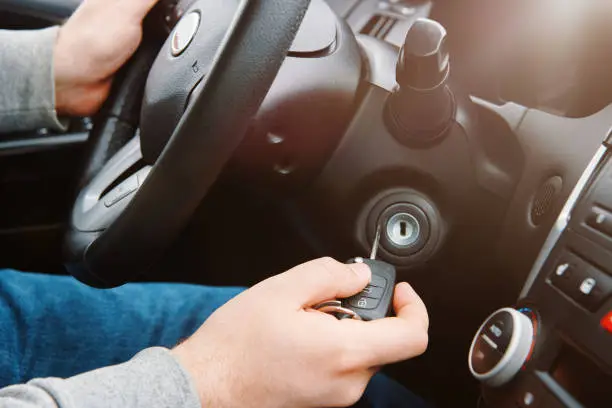 Man hand inserting car key into the keyhole to start the car. Starting the engine by the driver.