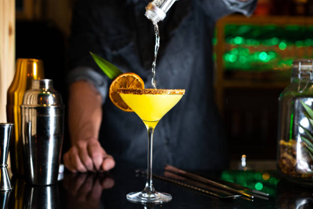 ナイトクラブバーでカクテルにアルコールを注ぐバーテンダー - cocktail orange cup juice ストックフォトと画像