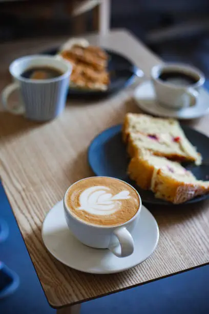 Photo of Coffee cups and cakes on table