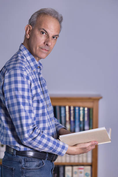 Portrait of a smiling Spanish middle-aged man, reading an interesting book with a smiling face.