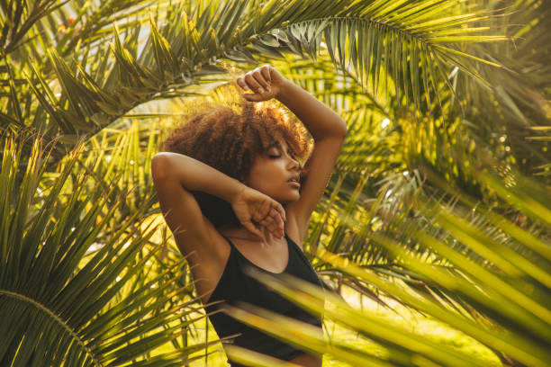 istock Pretty young afro woman among palm trees 1392610381