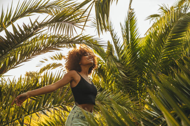 istock Pretty young afro woman among palm trees 1392610433