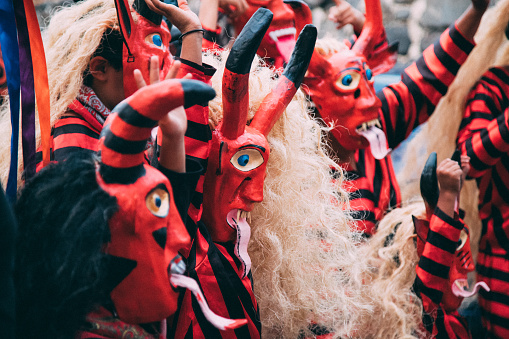 Zacualpan de Amilpas, Morelos, MEXICO- April 16, 2022: A troupe wearing handcrafted devil masks in the First Devil Festival in Zacualpan de Amilpas.  Zacualpan has a long tradition of cardboard and papier maché mask workshops. Each workshop makes a devil 3 to 4 meters tall, which they parade through the streets along with masked dancers and marching bands, that reach the main square and are burned with fireworks, as part of the catholic festivities of the Holy Week, in this case representing the triumph of good versus evil.