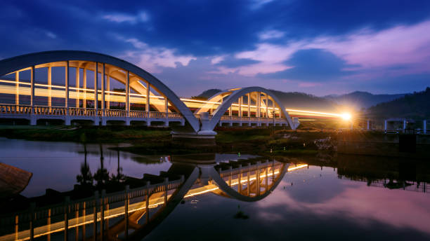 Long exposure Light from the train runs pass through bridge at dawn before sunrise , Tha Chom Phu white bridge is Landmark of the northern Thailand Long exposure Light from the train runs pass through bridge at dawn before sunrise , Tha Chom Phu white bridge is Landmark of the northern Thailand long shutter speed stock pictures, royalty-free photos & images