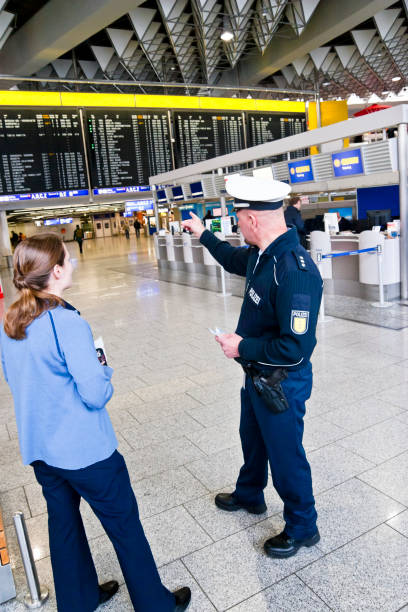 un oficial de policía en el aeropuerto asiste a una joven - ponytail brown hair tourist women fotografías e imágenes de stock