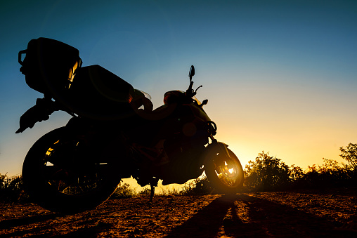 Silhouette a touring motorbike stands parking at sunset