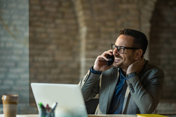 istock Happy businessman talking on phone while using laptop in the office. 1392616859