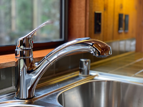 Chrome faucet on kitchen sink in rustic home