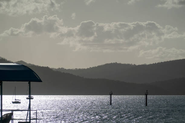 Early morning mist on the mountains and sunlight on the water offshore from a tourist resort. Opaque cloudy sky landscape.