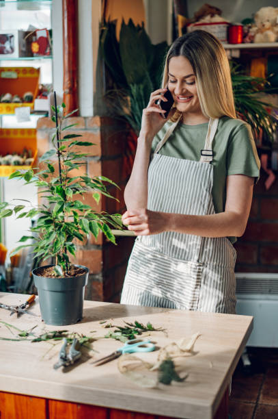 istock Woman florist using a smartphone while working in a flower shop 1392622425