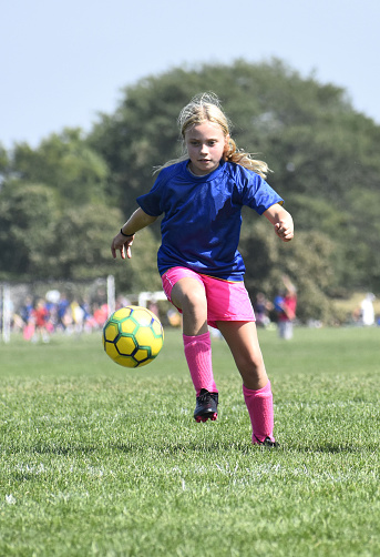 9 year old girl kicking soccer ball, autumn\nDowners Grove, Illinois  USA