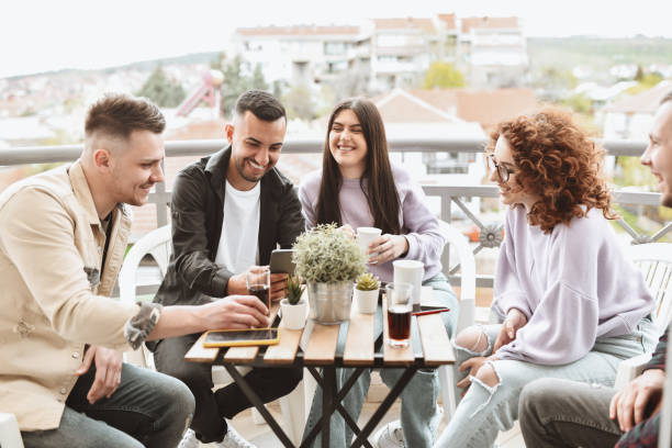 istock Happy Friends Having Refreshments While Hanging Out On Balcony Together 1392624069