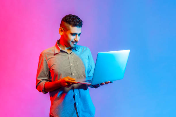 istock Man standing with portable computer in hand, looking at display, watching movie or video. 1392625571