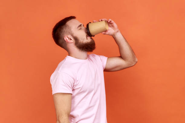 istock Sleepy man standing drinking coffee from disposable mug, need energy in morning. 1392625596