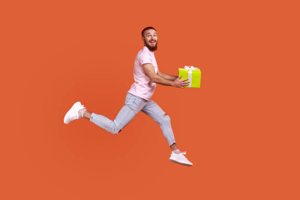 istock Man jumping in air or running quickly fast to give present box, expressing happiness. 1392625597
