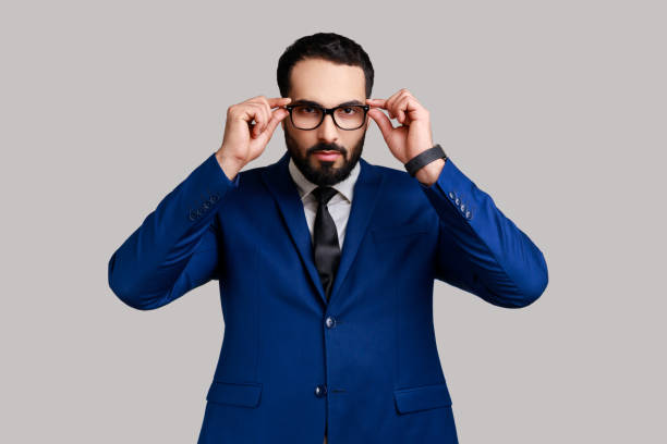 istock Bearded businessman putting off eyeglasses and looking at camera with bossy expression. 1392626340