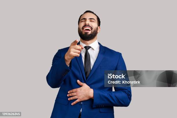 Bearded Man Laughing Out Loud Holding Belly And Pointing Finger On You Mockery Stock Photo - Download Image Now
