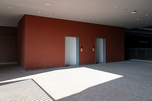 The side of the empty elevator entrance and the red walls have a lighting effect.