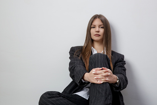 Studio portrait of fashionable girl in white button down shirt and striped oversized suit.