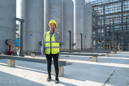 Female engineers use mobile phones to communicate in unfinished chemical plants