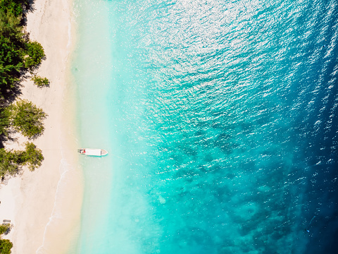 Beautiful tropical beach with turquoise crystal ocean and boat, aerial view.