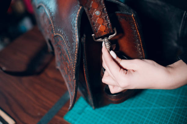 istock Tanner woman making leather goods on workshop. Working process of leather craftsman 1392636139