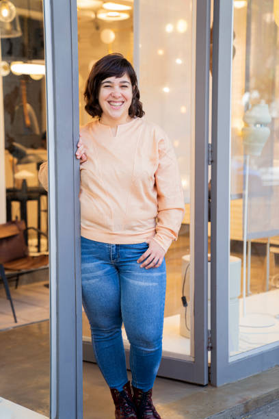 istock Young woman laughing while standing at store entrance 1392649171