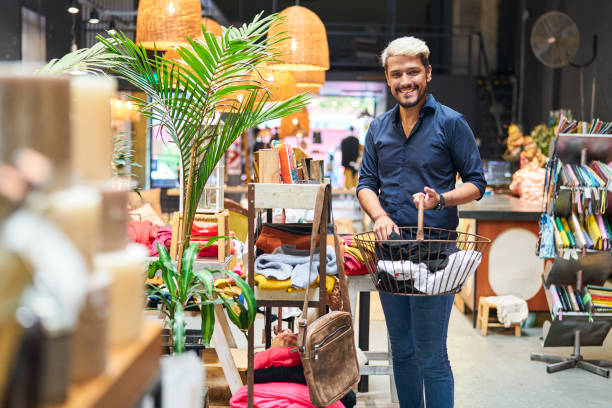 un homme latino-américain regardant la caméra alors qu’il faisait ses courses dans un magasin de vêtements - boutique store owner latin american and hispanic ethnicity photos et images de collection