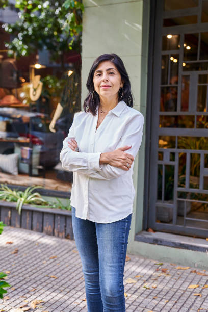 propriétaire de boutique latino-américaine confiante regardant la caméra debout à l’entrée du magasin - boutique store owner latin american and hispanic ethnicity photos et images de collection