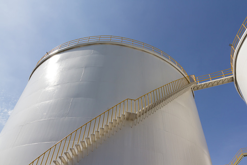 white oil tanks with yellow steel ladder. white steel petroleum silo, big liquid chemical container.