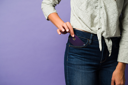 Hand of a young woman taking out her credit card from her jeans pocket to pay for at the store or while online shopping