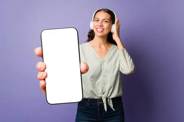 Relaxed young woman listening to music with headphones while using a music app on her phone