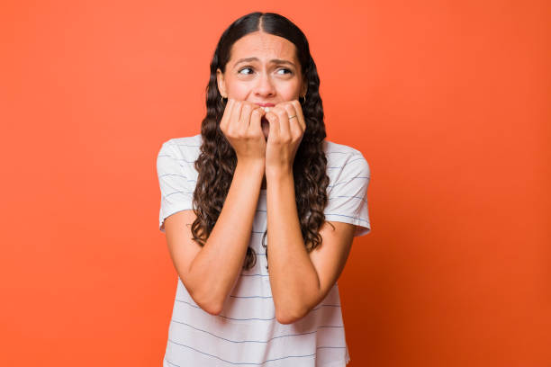 fearful woman watching something scary - nail biting imagens e fotografias de stock