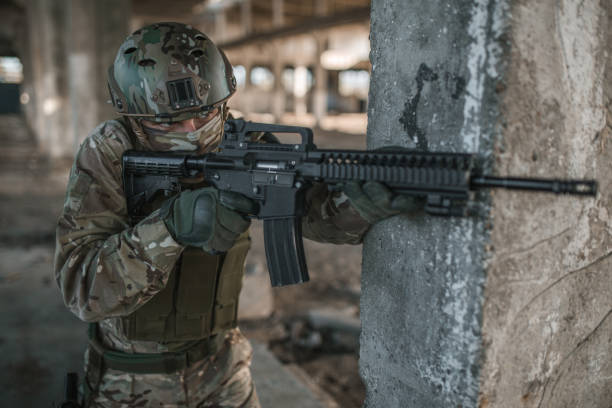 istock Unrecognizable soldier in camouflage uniform aiming with rifle in war zone 1392658686