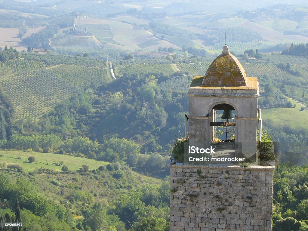 Bell Tower and Tuscan Landscape in San Gimignano Taken from the top of the Torre Grossa in San Gimignano, Italy, this shot shows the morning light over the Tuscan landscape beyond Agriculture Stock Photo