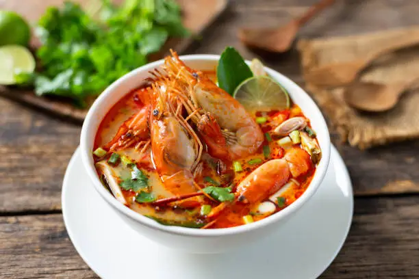 Photo of Tom Yam Kung ,Prawn and lemon soup with mushrooms, thai food in wooden bowl top view