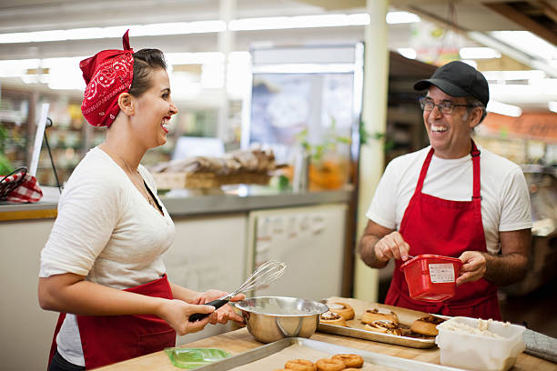 Young woman and man laughing in commercial kitchen  baker occupation stock pictures, royalty-free photos & images