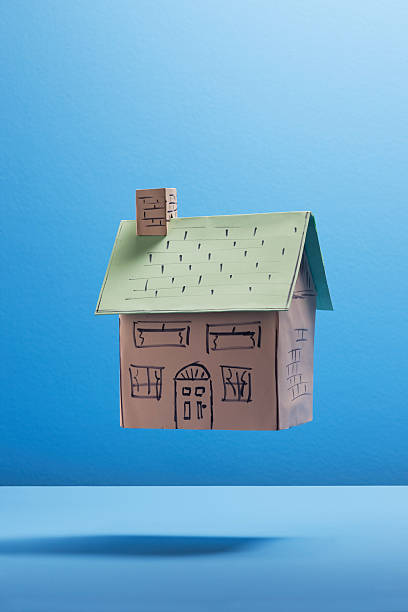 Floating cardboard house against blue background  cardboard house stock pictures, royalty-free photos & images