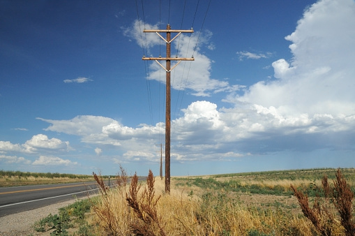 Rural Colorado highway landscape with telephone pole and lines with blue sky and clouds