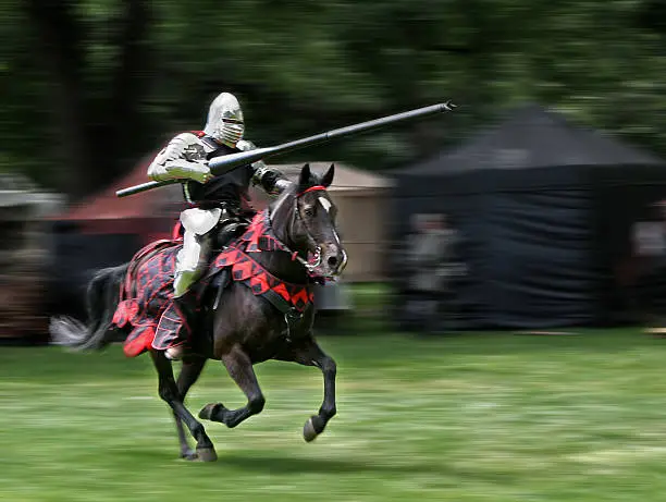 Armored rider with lance on horse. Motion blurred background.